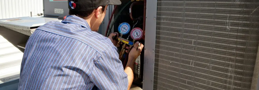 HVAC technician servicing a condenser unit in Redding