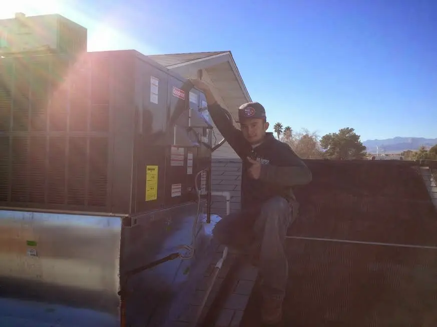 HVAC technician performing Air Duct Cleaning on a rooftop unit in Redding
